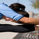 Young athletic Asian women stretching outdoors in a public park.